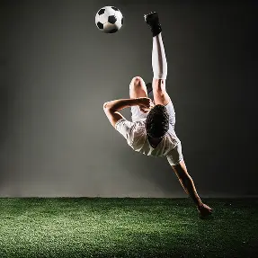 Atleta a executar um impressionante pontapé de bicicleta enquanto joga futebol num campo desportivo profissional.
